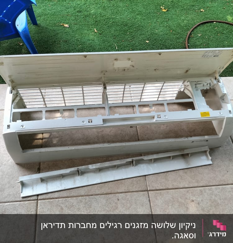 חלקי מזגן מפורקים על רצפה מרוצפת